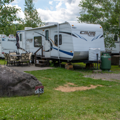 Roulotte Four Winds (Lot 438) stationnée sur un terrain boisé avec table de pique-nique