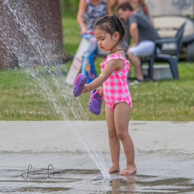 Fille marchant près d’un jet d’eau Jeune fille marchant autour d’un jeu d’eau au camping familial