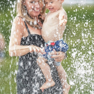 Mère tenant un enfant sous une douche d’eau Maman et enfant sous les jets d'eau au camping en Estrie