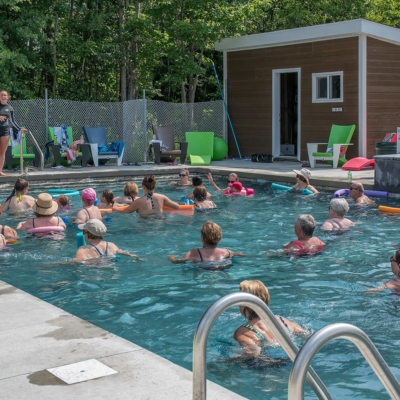 séance d’aquagym au Camping Magog Orford Groupe d’adultes en pleine séance d’aquagym au Camping Magog Orford, encadré par une animatrice devant le pavillon de la piscine