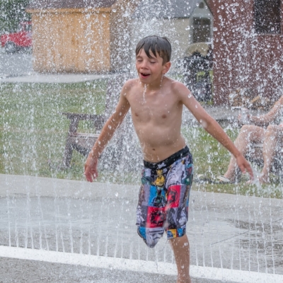 Jeux d’eau rafraîchissants pour enfants au Camping Magog Orford Garçon qui joue sous un jet d’eau au Camping Magog Orford