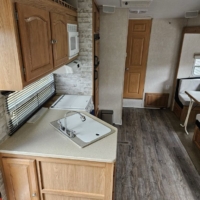 Coin repas et cuisine avec évier, plan de travail et banquette – Roulotte De Parc 435