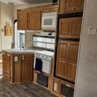 Cuisine en angle avec micro-ondes et armoires en bois – Roulotte De Parc 435